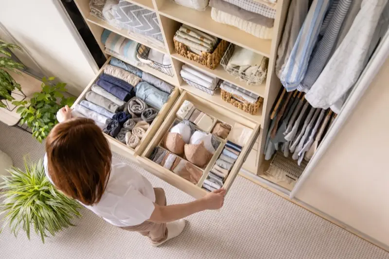 Overhead view of an organized closet drawer system with folded clothing