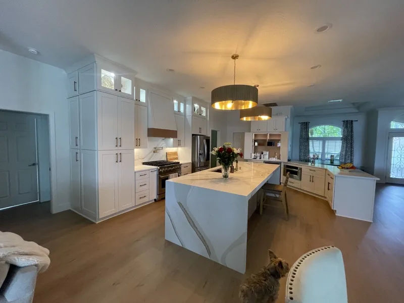 Kitchen island with white waterfall quartz top and gold pendants