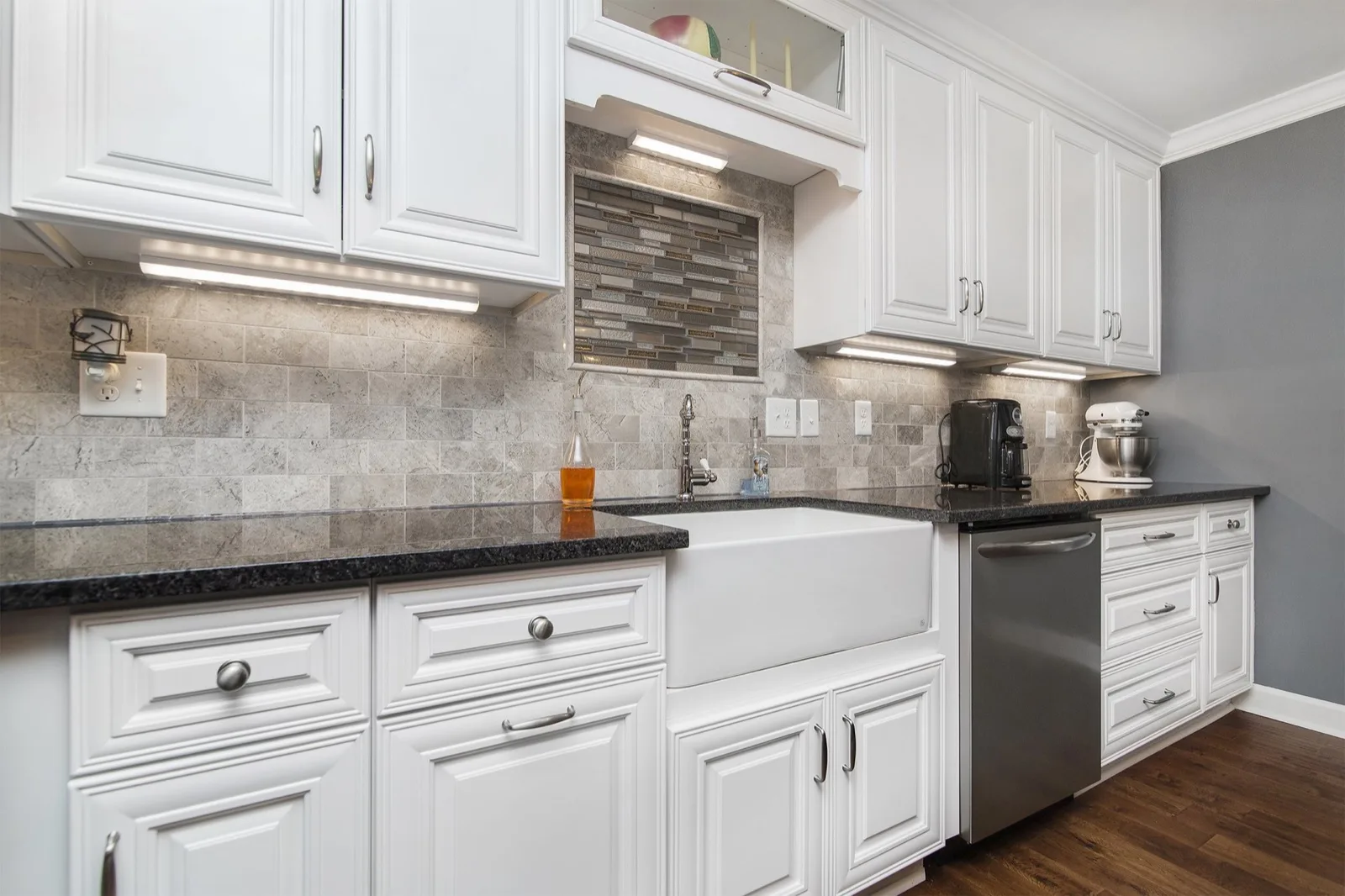 White shaker kitchen we installed in Tampa Bay: farmhouse sink, black granite counters and under-cabinet lighting