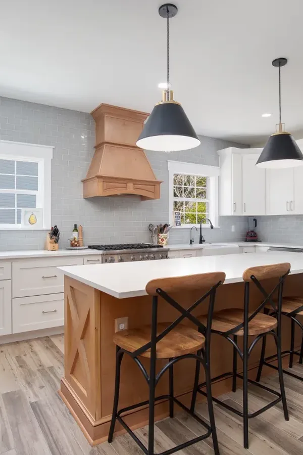 Kitchen with white shaker cabinets, wood island, and gray subway tile backsplash